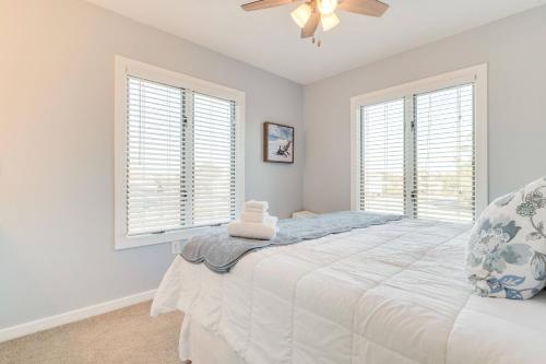 a bedroom with a bed and two windows at Sounds Great! in Duck