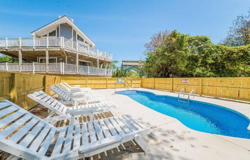 a swimming pool with chaise lounge chairs and a house at Sounds Great! in Duck