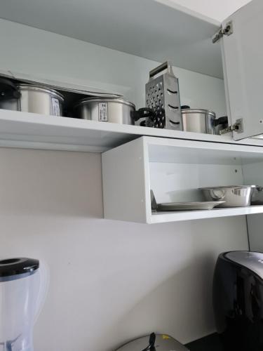 a kitchen with white shelves with pots and pans at Apartamento com Wi-Fi e lazer completo in Ananindeua