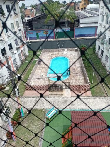 a view of a swimming pool through a fence at Apartamento com Wi-Fi e lazer completo in Ananindeua