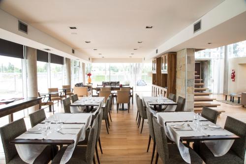 a dining room with tables and chairs and windows at Herradura Hotel Suites in Neuquén