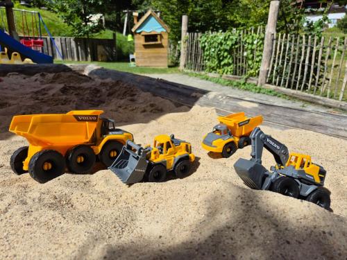 three toy dump trucks in the sand on a playground at Haus Hees in Todtnau