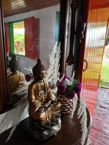 a statue of a buddha sitting on a table with flowers at Eco Hotel Rancho J en Tulua Valle in Morales