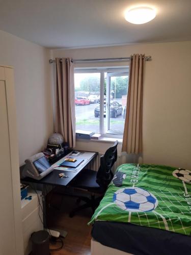 a bedroom with a bed and a desk and a window at Fabulous two bedroom flat with concierge in Dagenham