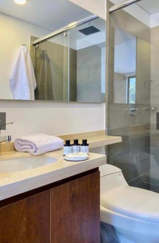 une salle de bain avec un lavabo, des toilettes et un miroir dans l'établissement Tekto Apartamento con Balcón y Vista hermosa a las montañas de Bogotá, à Bogotá