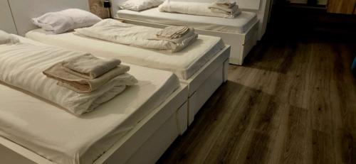 three beds with white sheets and towels on them at Pensiunea Alina-Maria in Vîrfurile