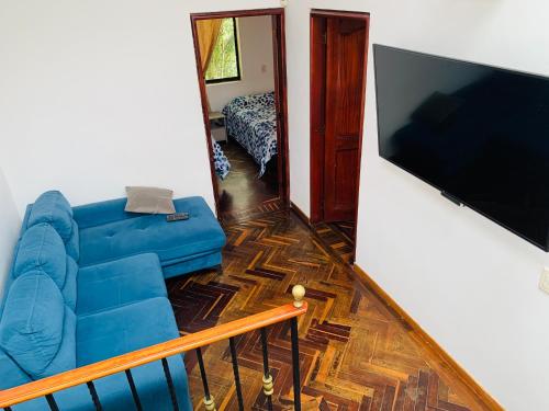 a living room with a blue couch and a flat screen tv at Casa Campestre Poblado para 10H San Lucas 106 in Medellín