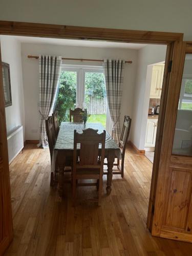 a dining room with a table and chairs and a window at 49 Dunalinn Culdaff in Balnacart
