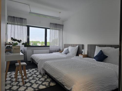 a white bedroom with two beds and a desk at Large apartment near Munich in Ismaning