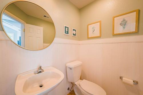 a bathroom with a sink and a toilet and a mirror at Currituck Carl's in Sanderling