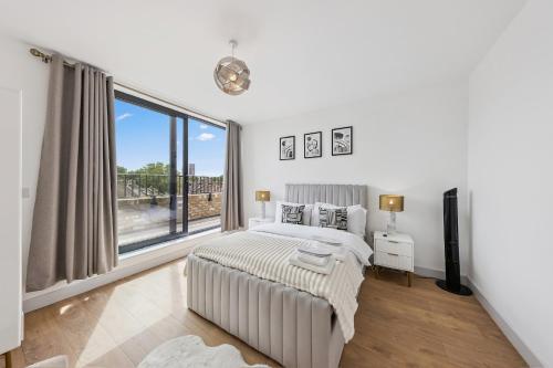 una camera da letto con un letto e una grande finestra di Hobson Woods Apartments a Londra