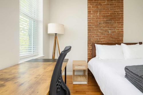 a bedroom with a bed and a desk with a chair at Stylish 2BR Apartment with Private Balcony near Soulard in Saint Louis