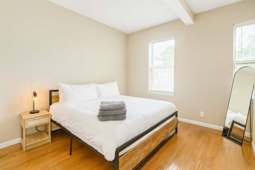 a bedroom with a bed with white sheets and a mirror at Stylish 2BR Apartment with Private Balcony near Soulard in Saint Louis