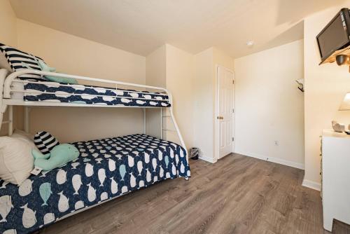a bedroom with two bunk beds and a wooden floor at Follow the Sun in Duck