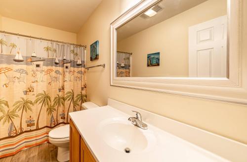 a bathroom with a sink and a toilet and a mirror at Follow the Sun in Duck