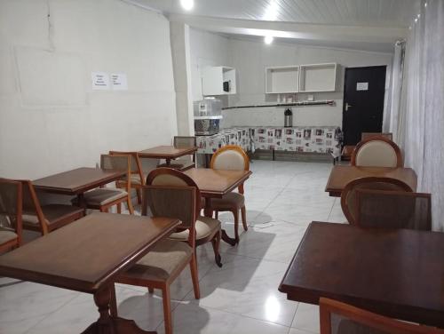 a classroom with wooden tables and chairs and a kitchen at Hotel Pousada Central Campo Grande in Campo Grande