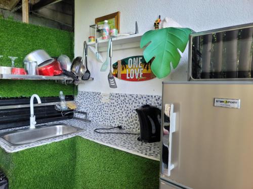 a green kitchen with a sink and a refrigerator at Beach house minutes from Ochi Rios and Ian Fleming airport in Salt Gut Pen