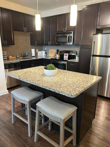 a kitchen with a granite counter top island with two stools at 2 Bedroom Boutique Apartment in the Heart of Charlotte in Charlotte