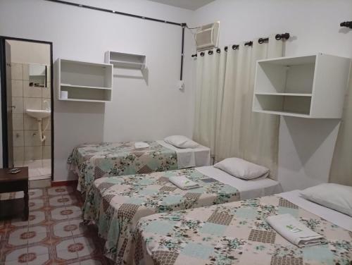 ein Hotelzimmer mit zwei Betten und einem Spiegel in der Unterkunft Hotel Pousada Central Campo Grande in Campo Grande