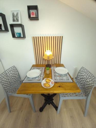 a wooden table with two chairs and a lamp on it at Studio Proche Centre ville avec Place de Stationnement in Montélimar