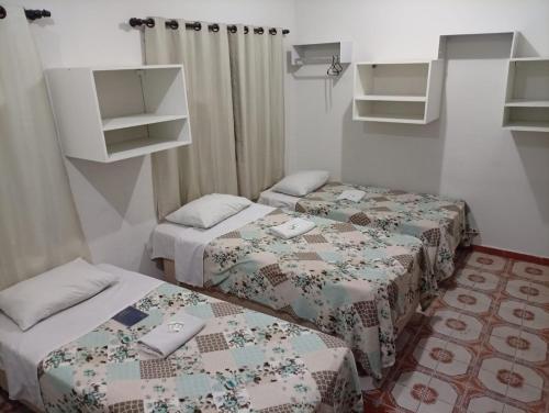 two beds in a small room with a room with two beds at Hotel Pousada Central Campo Grande in Campo Grande