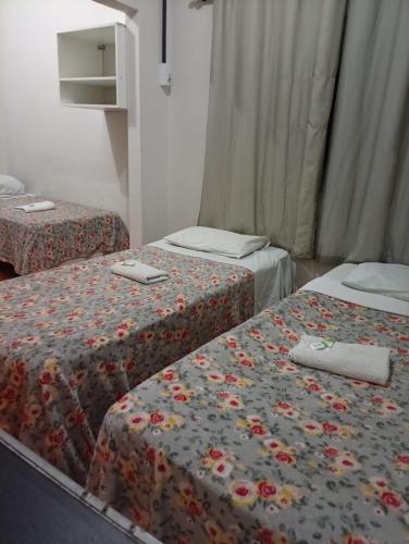 a room with two beds with flowers on the covers at Hotel Pousada Central Campo Grande in Campo Grande