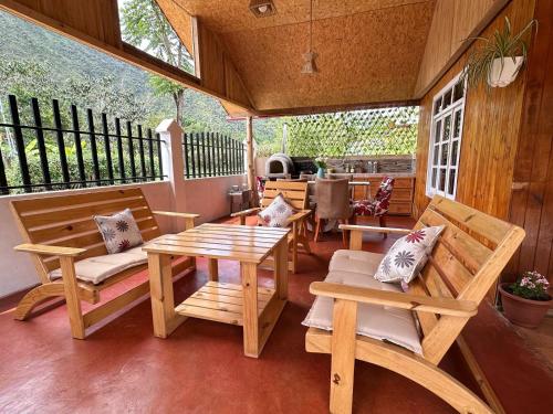 a porch with wooden furniture and a table and benches at La posada del Minero - Oxapampa in Oxapampa