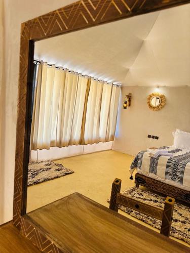 a mirror reflection of a bedroom with a bed in it at Merzouga traditional Camp in Merzouga