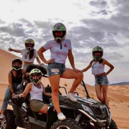 a group of people standing on the back of a quad bike in the desert at Merzouga traditional Camp in Merzouga