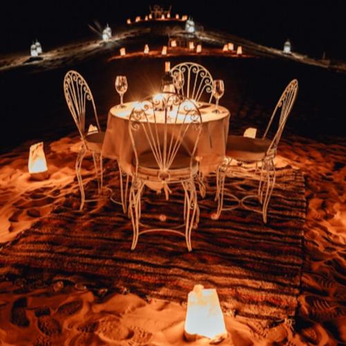 a table with chairs and wine glasses on it at Merzouga traditional Camp in Merzouga