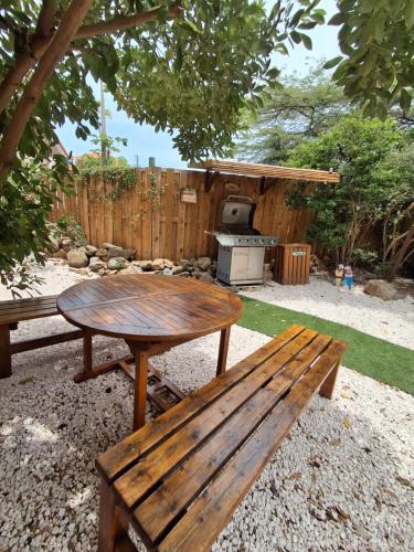 a picnic table and bench in a backyard with a grill at Casita Tres Trapi in Noord