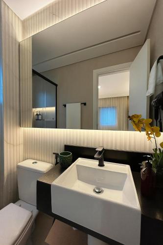 a bathroom with a white sink and a mirror at Flat Praia do Canto 2Q-2B Long Stay TRIÂNGULO DAS BERMUDAS in Vitória