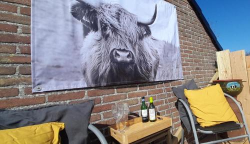 a picture of a cow hanging on a brick wall at Pipowagen bij Sneek, voor maximaal 2 personen in Hommerts