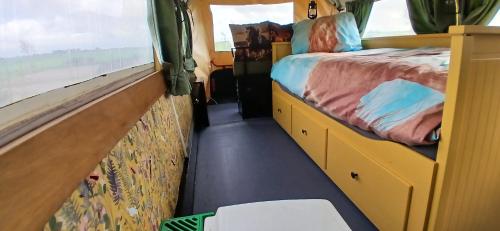 a small bedroom with a bed and a window at Pipowagen bij Sneek in Hommerts