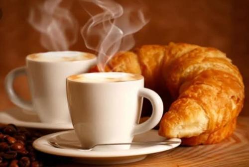 two cups of coffee and a croissant on a table at MA.DI BB in Rocca San Giovanni