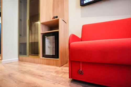 a red couch in a living room with a fireplace at The MONT BOUTIQUE HOTEL in Shkodër