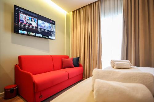 a hotel room with a red couch and a tv at The MONT BOUTIQUE HOTEL in Shkodër