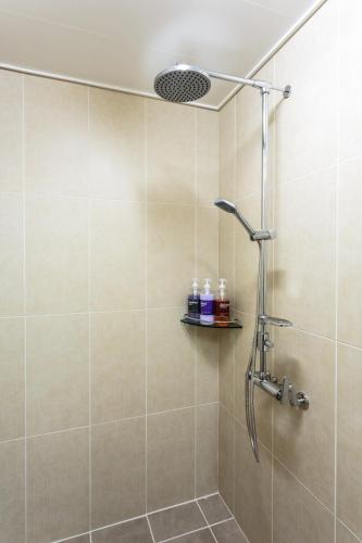 a shower with a shower head in a bathroom at Goraesu Pension in Seogwipo