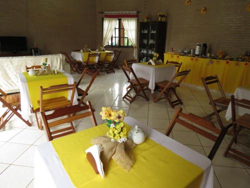 a dining room with tables and chairs with yellow tables at Pousada Recanto do João de Barro in Conservatória