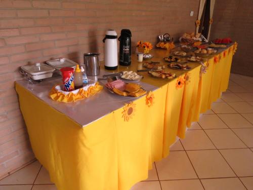 a table with a yellow table cloth and food on it at Pousada Recanto do João de Barro in Conservatória