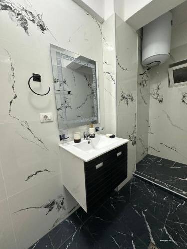 a white bathroom with a sink and a mirror at Papa's Apartment in Korçë