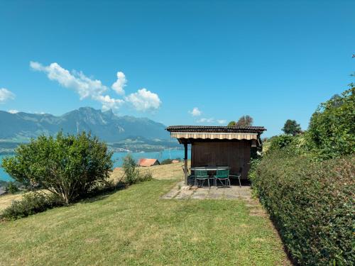 a small hut with a table and chairs on a hill at Chalet with pool and view of Lake Thun in Aeschlen ob Gunten