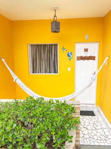 a yellow house with a hammock in front of a door at Pousada Flor de Merepe - Porto de Galinhas in Porto De Galinhas