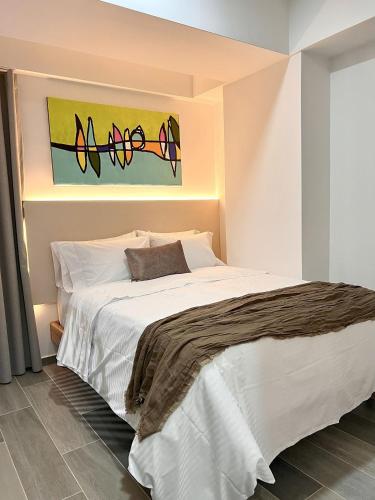 a bedroom with a white bed with a painting on the wall at BIT by Simple stay in Medellín