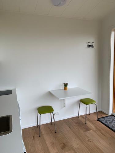 a living room with two green chairs and a table at Skammidalur cottages in Vík
