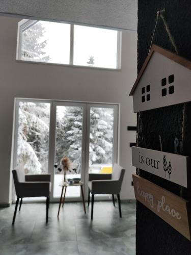 a living room with chairs and a table and windows at Lux Escape Pridolci in Kozica