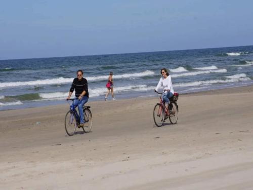 two people riding bikes on the beach at 4 star holiday home in Blokhus-By Traum in Blokhus