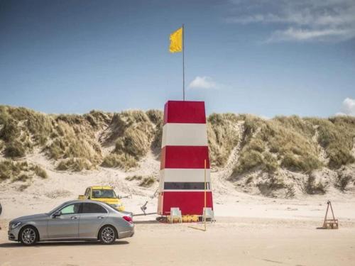 a car parked next to a lighthouse on the beach at 4 star holiday home in Blokhus-By Traum in Blokhus