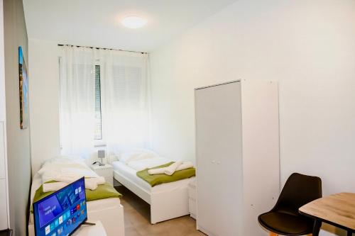 a small white room with a bed and a desk at Ok Apartments in Pforzheim