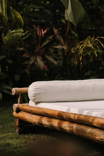 a wooden bed with white sheets in a garden at UNLTD Siargao Hotel in General Luna